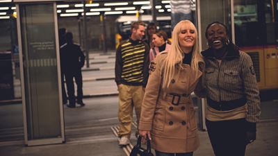 Two women laughing at the PostBus station