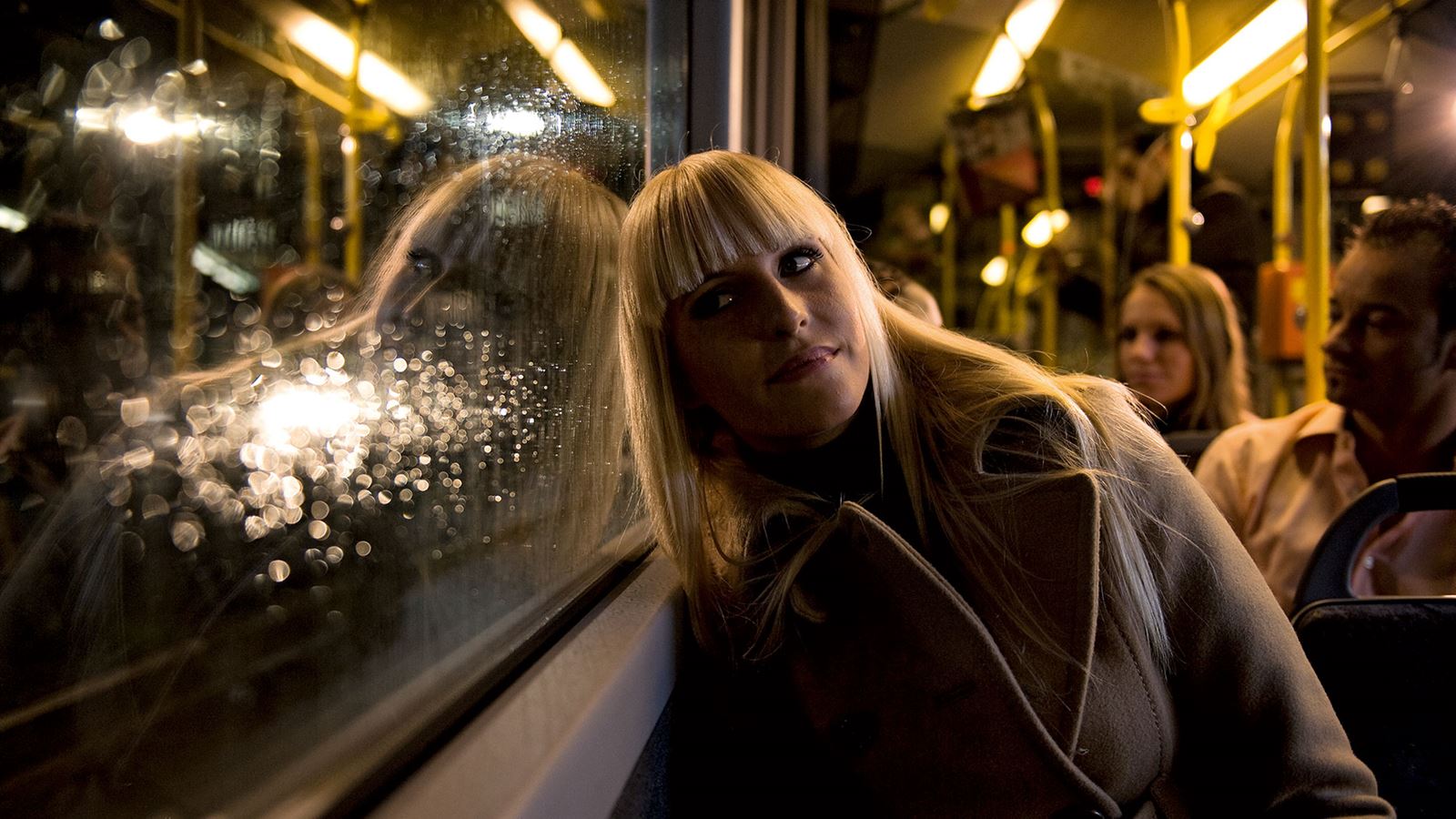Eine junge Frau sitzt in einem Postauto. 