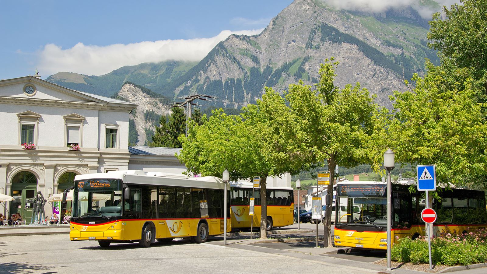 Bad Ragaz railway station in the summer with three Postbuses, all of which depart promptly.