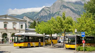 Bad Ragaz railway station in the summer with three Postbuses, all of which depart promptly.