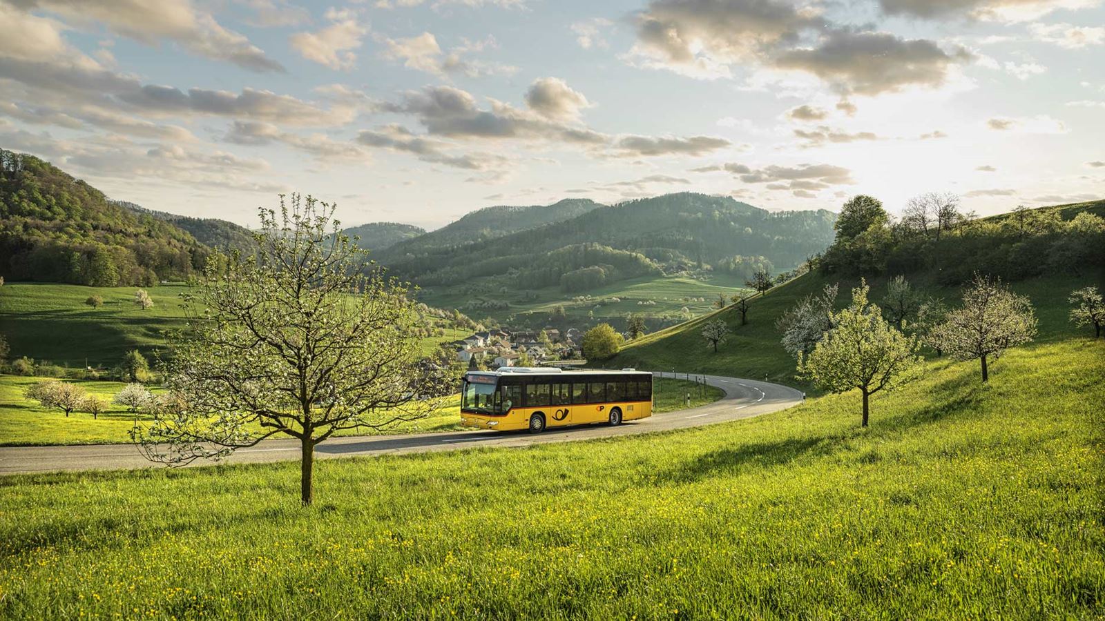 A Postbus on a bend in a green hilly landscape