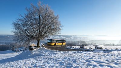Das Postauto fährt im Winter über den Albispass