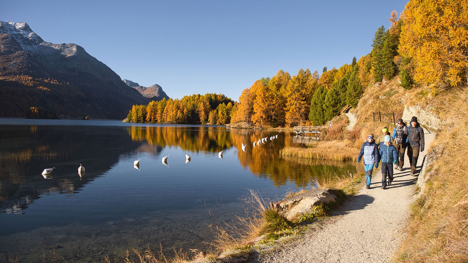 Eine Familie wandert während einem schönen Herbsttag an einem Bergsee entlang.