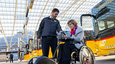 A Postbus driver showing a woman in a wheelchair something on her mobile phone