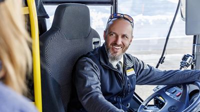 A Postbus driver smiling at a person getting on to the Postbus