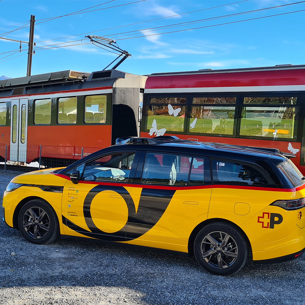 Il veicolo AmiGo si trova accanto a un treno su una tratta ferroviaria nelle aree rurali.