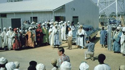 L’Emir di Kano con la sua Cadillac, circondato da tante persone con il velo e vestiti lunghi.