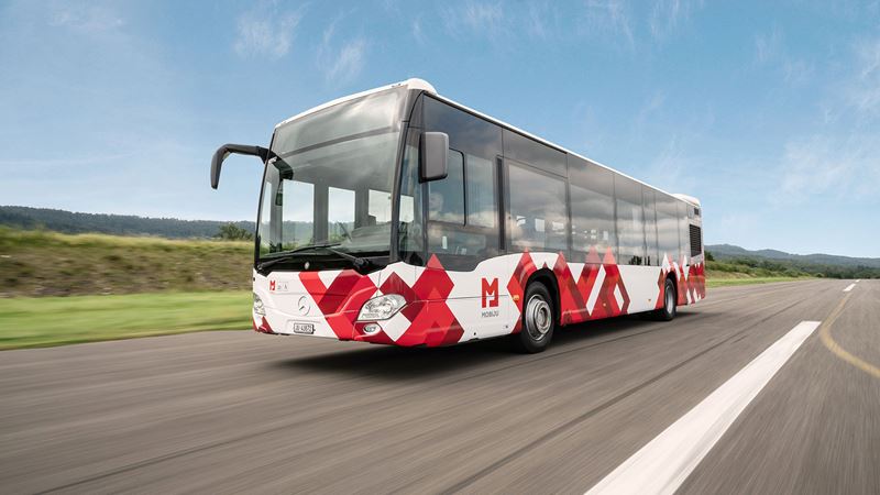 A bus on the road in Jura, decorated in the red and white MOBIJU design. 