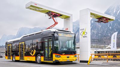 An electric Postbus is charged at the train station