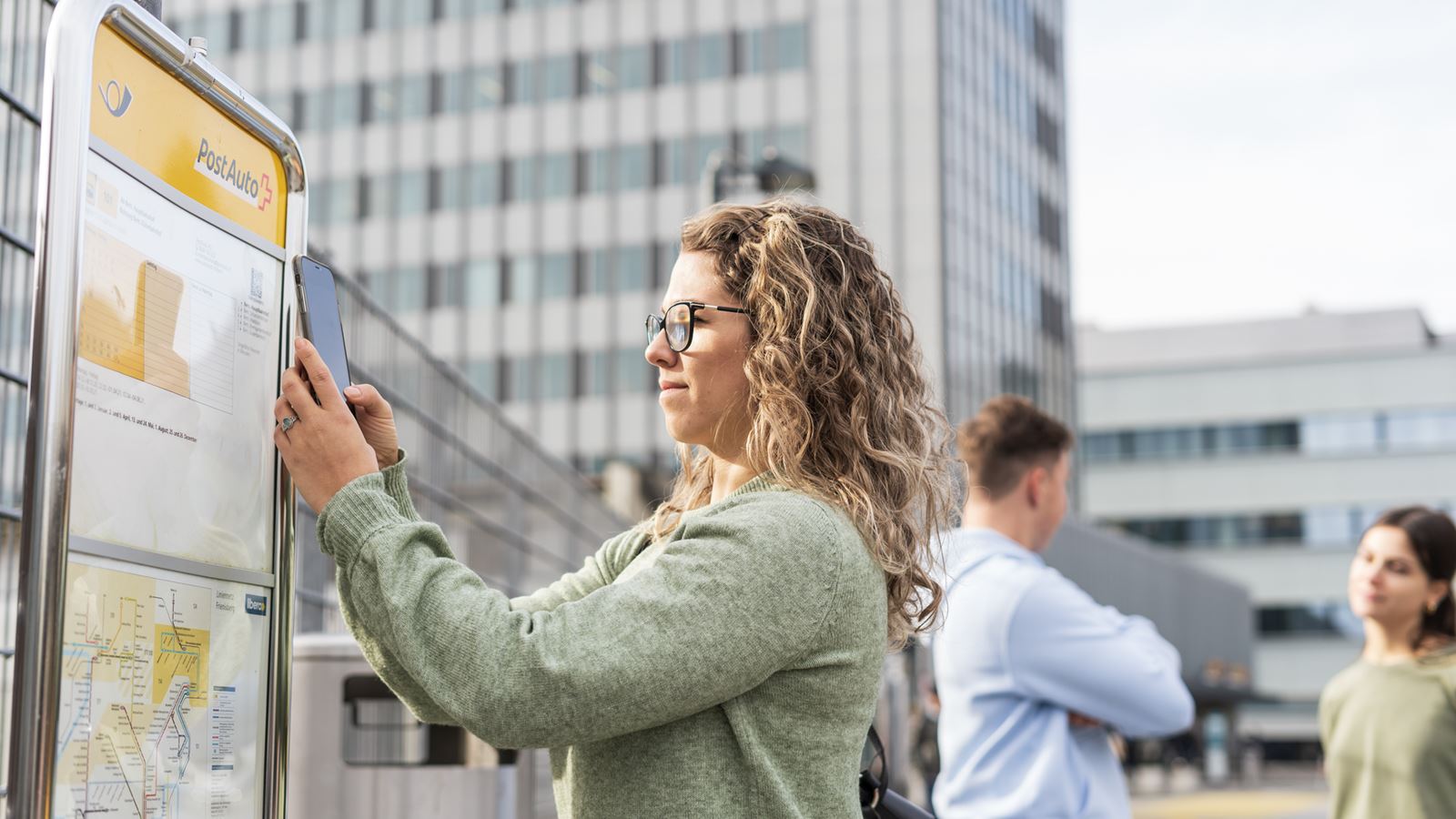 Una donna scansiona con il cellulare il codice QR dell’orario alla fermata dell’autopostale a Berna.