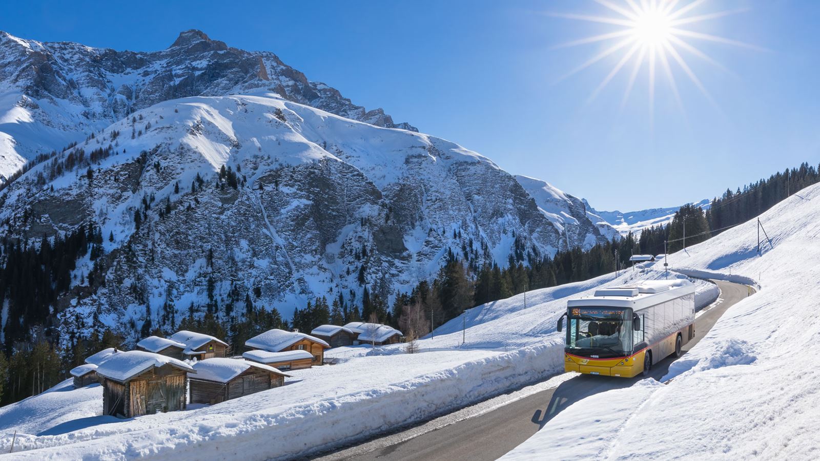 Un car postal circule dans une vallée enneigée des Grisons par un magnifique temps hivernal.
